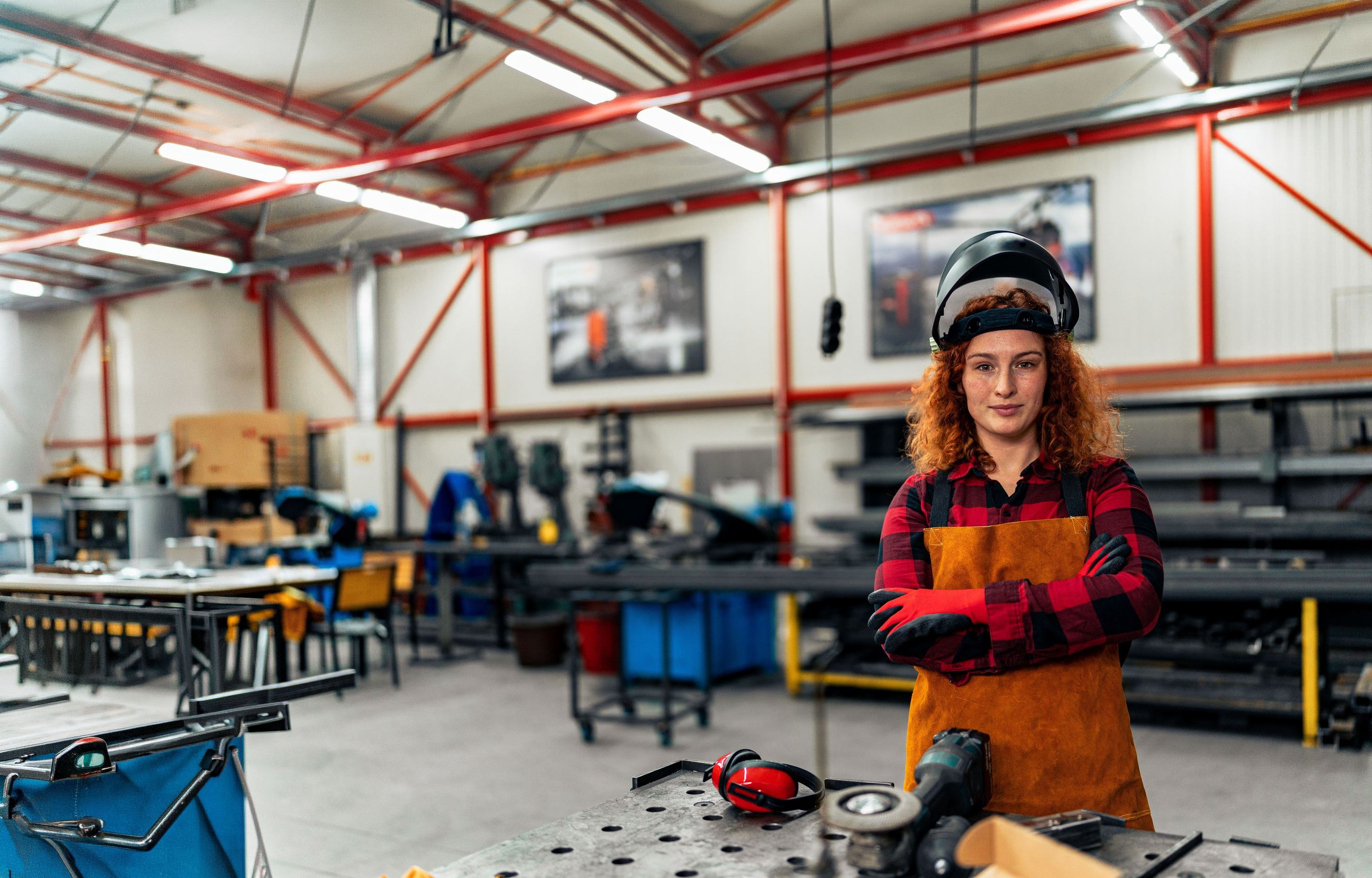 A workshop owner standing at her bench, arms crossed